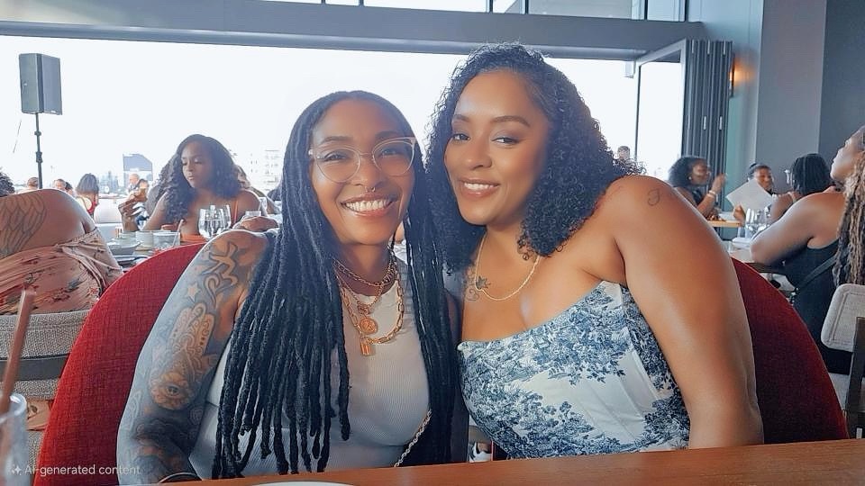 Two women smiling together at a restaurant, with a lively atmosphere in the background.